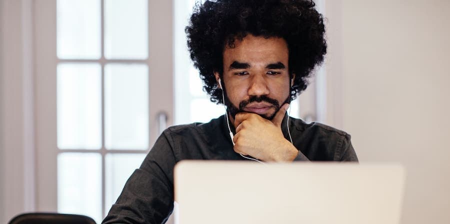 man with earbuds looking at laptop screen