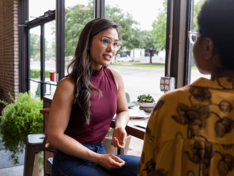 Woman having conversation with female colleague in a coffee shop.
