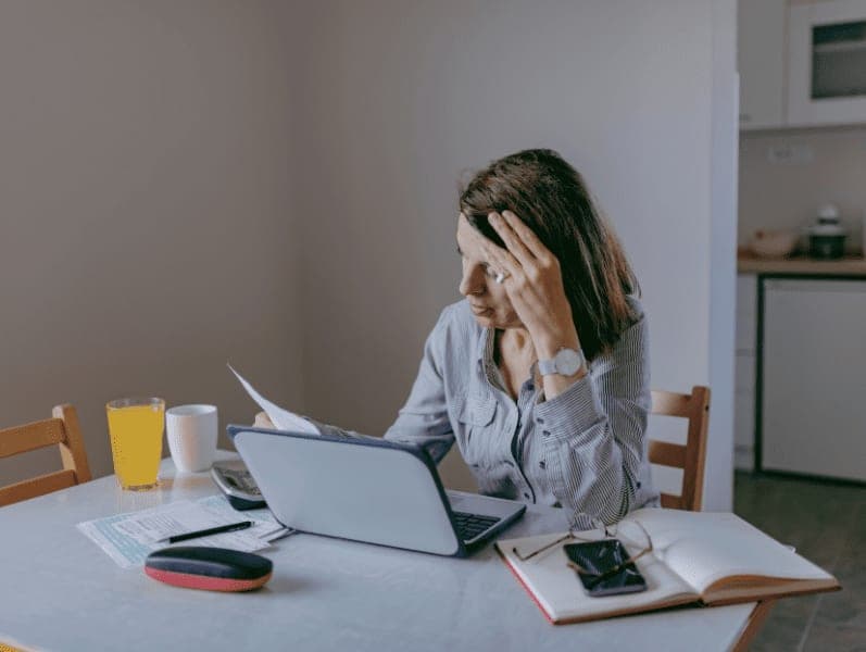 Stressed woman going through bills, looking worried.