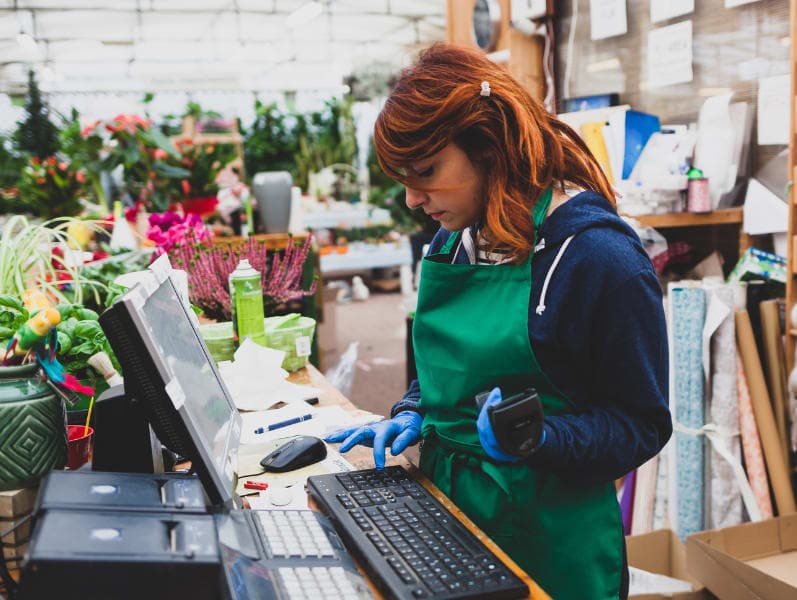 Young florist with red hair works in a nursery.