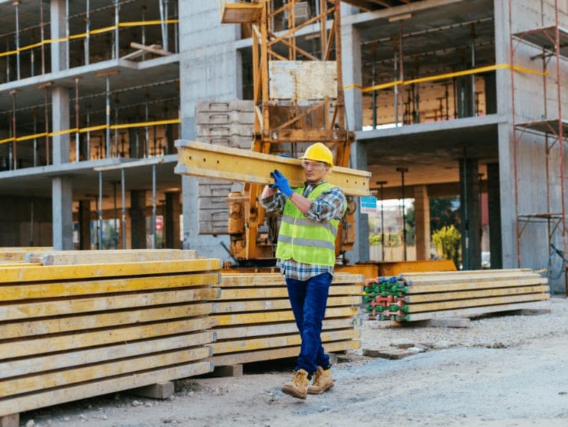 Construction worker lifting steel on construction site.