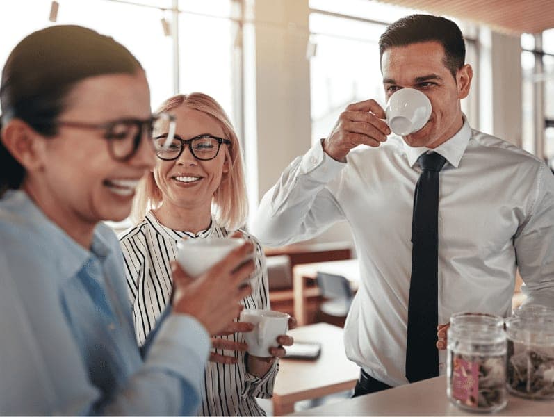 Group of young businesspeople laughing together during their coffee break in a bright modern office.
