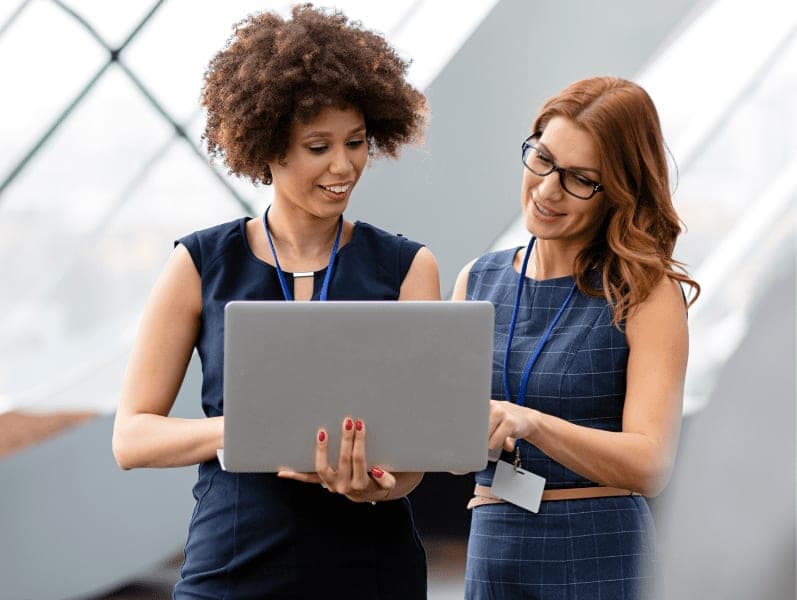 Business people standing while using a laptop.