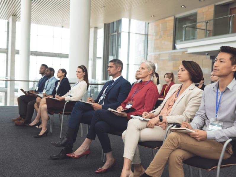 Side view of diverse well dressed business people attending a business seminar in office building.