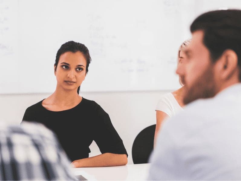 Business people sitting at conference table, focus is on serious female executive.