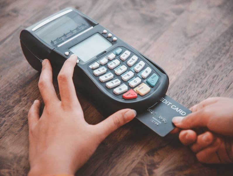 Close-up shot of woman's hands using a credit card swipe machine.