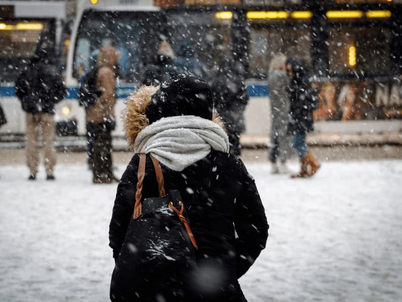 People walking on snow covered city street.