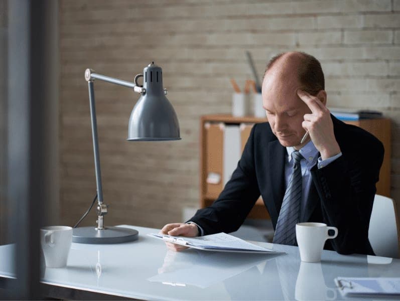 Mid adult boss reading document in personal office.