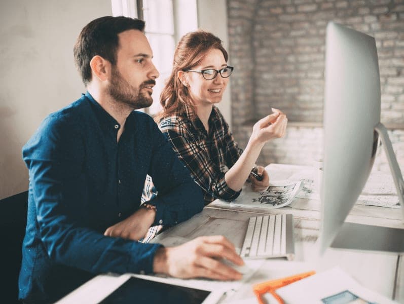 Company employees working in front of a desktop computer.