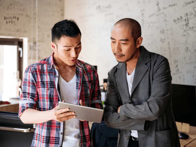 Standing colleagues discussing work using a digital tablet.