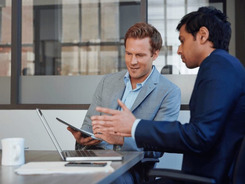 Two businessmen having a discussion on laptop in the office.