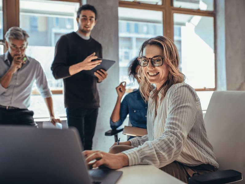 Female employee giving a presentation using her laptop at meeting with colleagues.