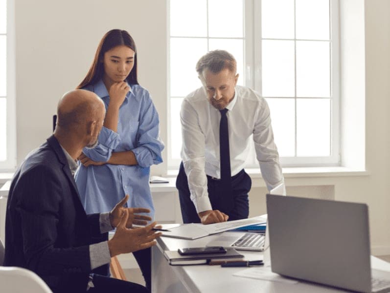 Three employees talking about work in office.