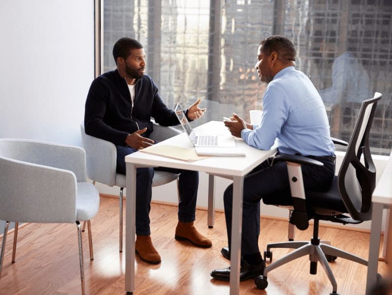 Man having a meeting with male advisor in an office.
