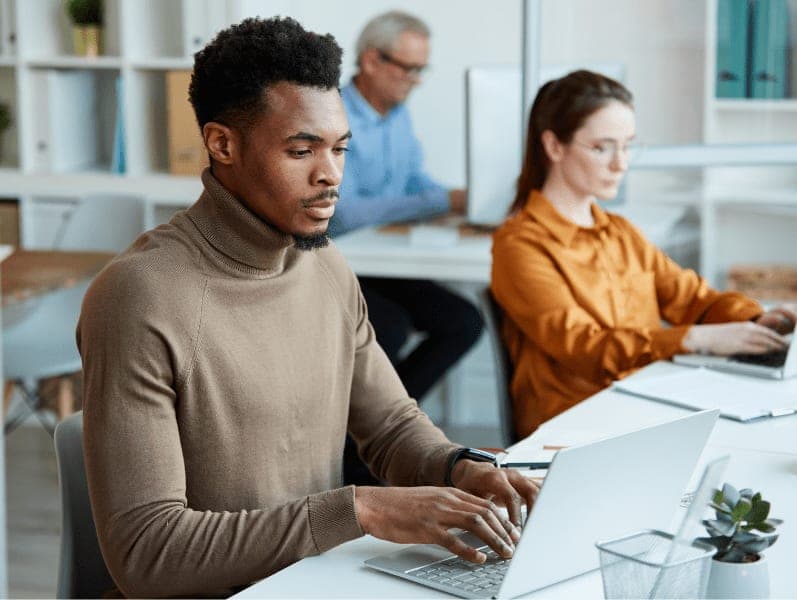 Business people sitting on their workplaces and typing on laptop computers at the office.