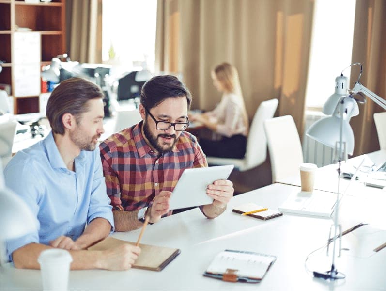 Two male employees with tablet discussing business