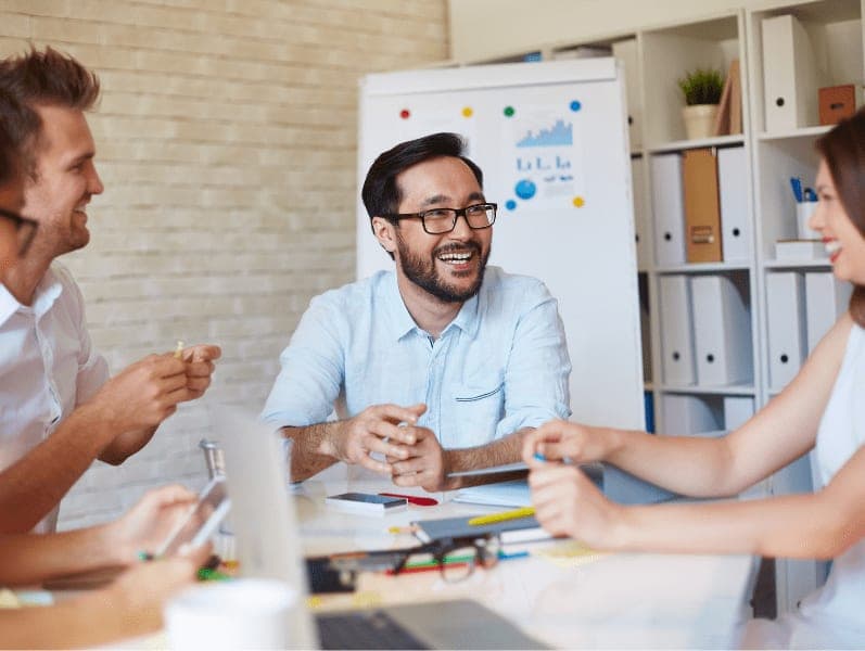 Happy Asian businessman talking to colleagues at meeting