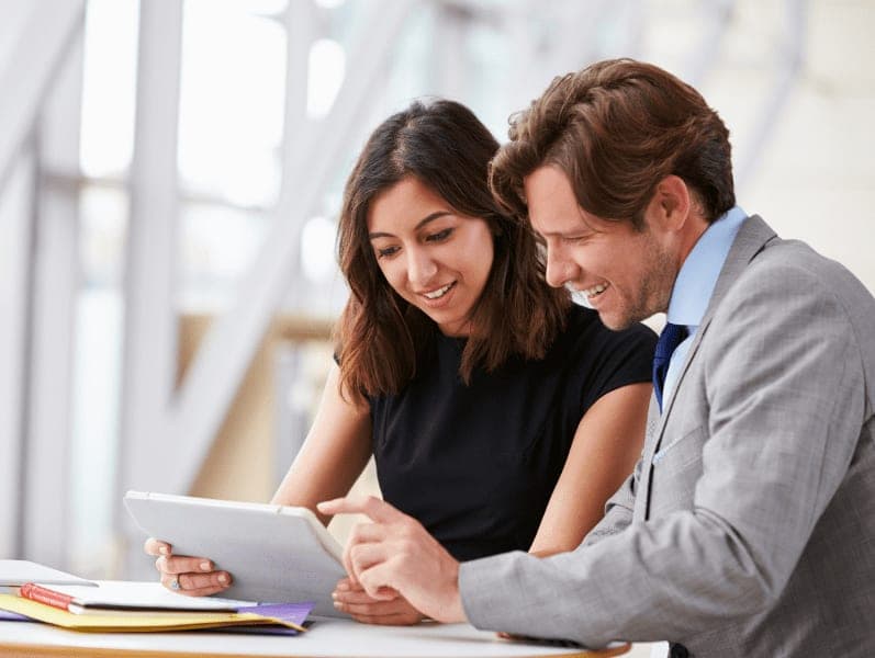 Two corporate business colleagues using a tablet having a discussion in the office