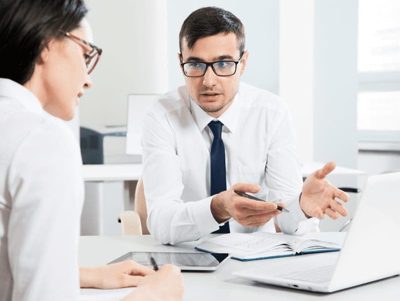 Colleagues sitting on the desk having a conversation with a laptop