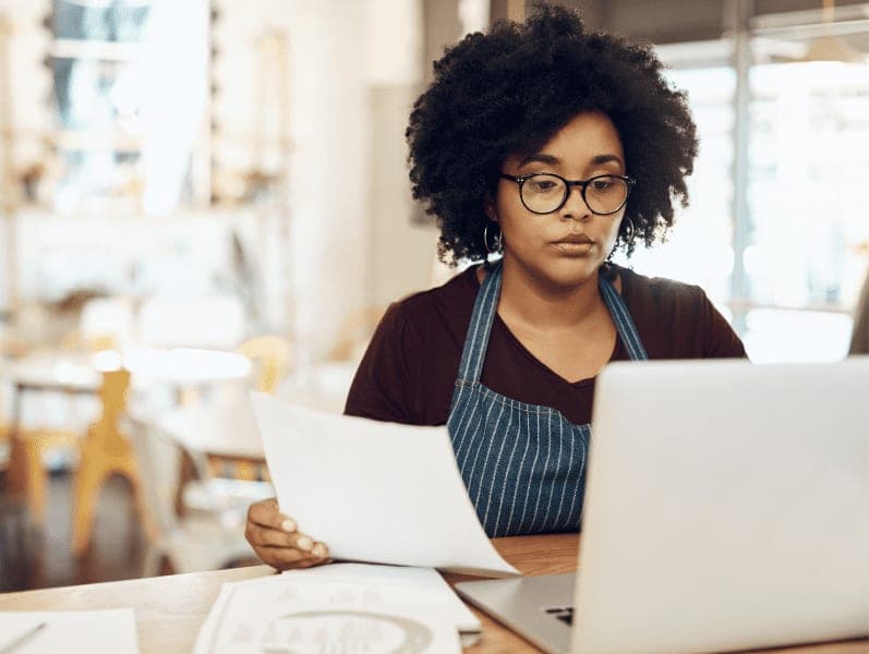 Young cafe owner using her laptop and doing paperwork in her shop