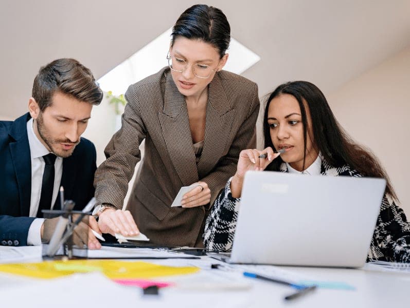 Three office workers having a discussion with a laptop