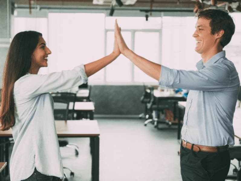 Happy business colleagues giving five as symbol of success and good job