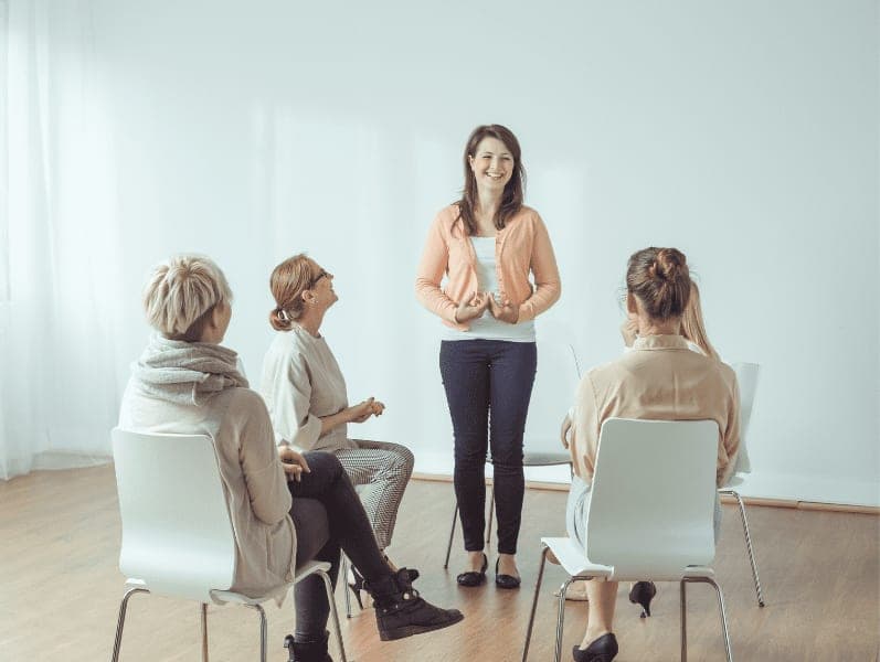 happy young woman standing in front of support group