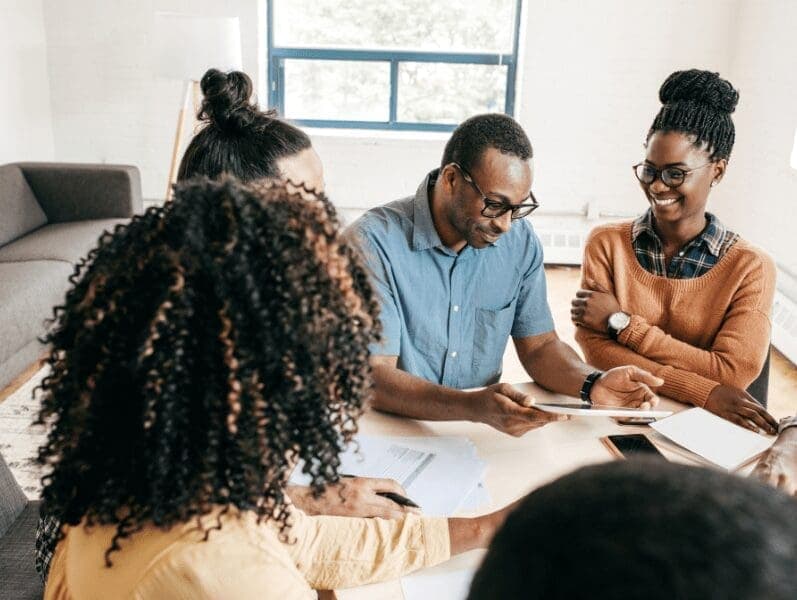 Team of people sitting around a table discussing the Reality to Become a Conscious Advisor