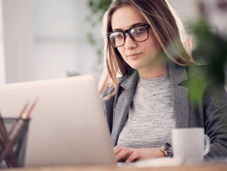 Female sitting at desk in front of lap top reviewing Cybersecurity