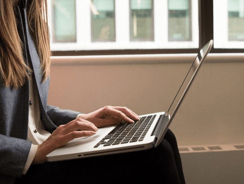 Torso side view of woman sitting with lap top on her knees