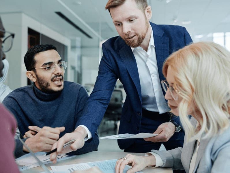 Male colleague helping team members review leadership competencies
