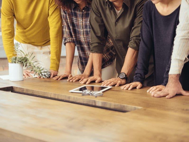 four employees standing along a desk all looking at table with a clients timesheet