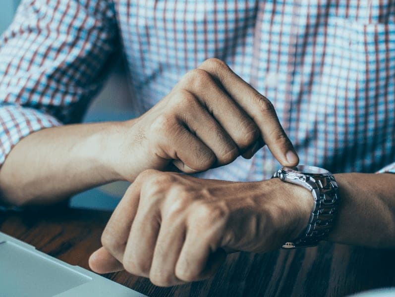 Man point to wait on wrist refencing the time he has to manage his projects