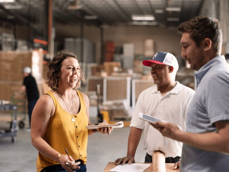 Female employee speaking with male colleagues in a warehouse setting