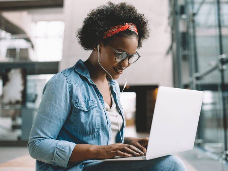 Woman sitting in an open are with laptop and headphones in study for an exam
