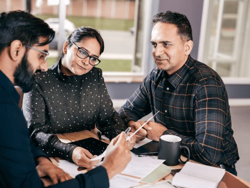 Man speaking with male and female colleague reviewing numbers