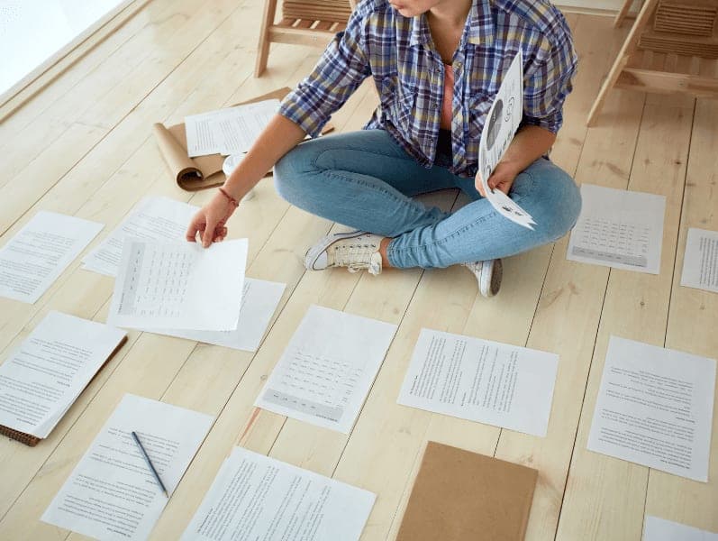 Woman sitting on floor with a bunch of papers financial papers on the floor
