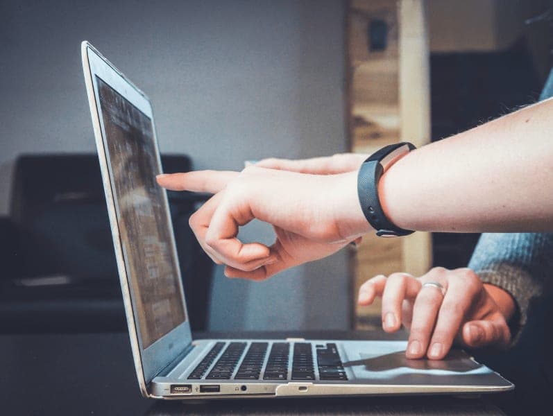 Tw people working on a lap top with only a side view of their hands