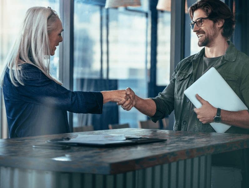 Man and female shaking hands across a table