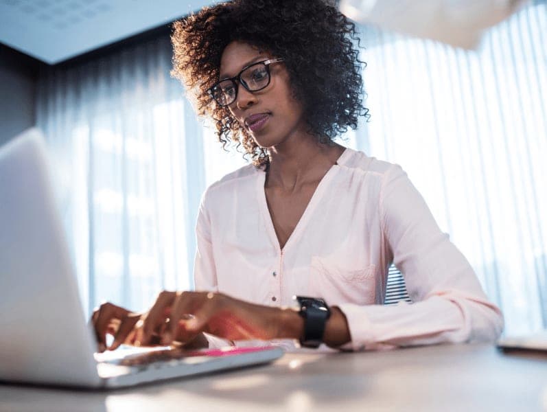 Female sitting at desk with a laptop updating her cybersecurity software