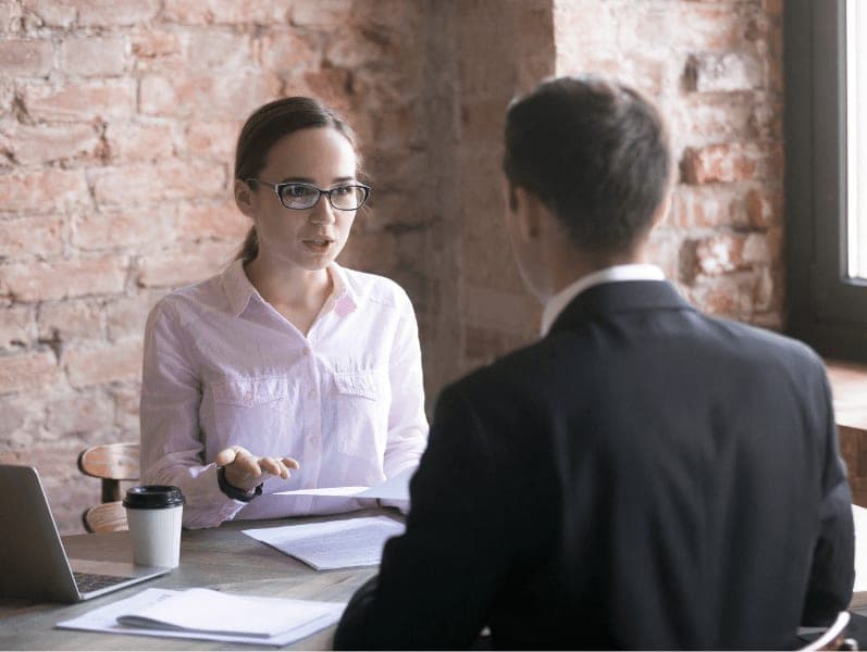 Accountant sitting at her desk and advising a male small business owner.