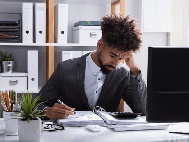 Young male accountant anxiously calculating his firm's revenue.