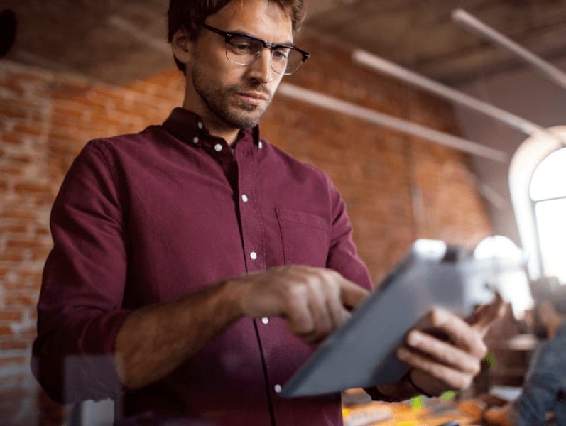 Man standing holding a tablet previewing a document on it