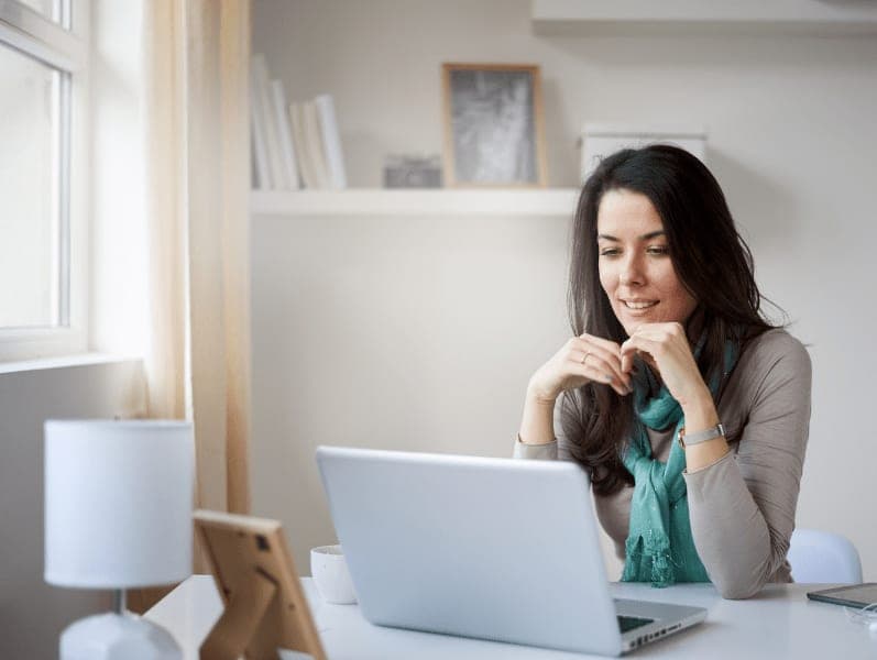 Woman in home office in front of laptop smilling