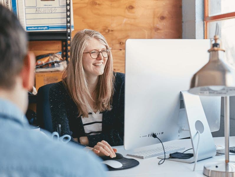 Female accounting employee sitting in at desk refernceing desktop screening while working with client