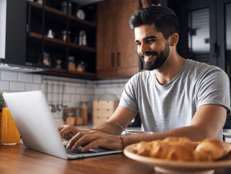 Male freelancer sitting at kitchen island working on laptop