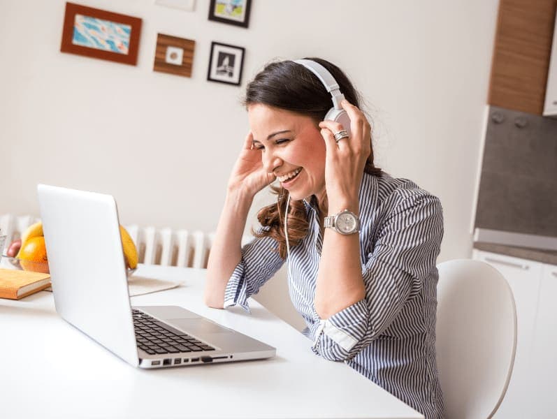 Portrait view of female sitting at kitchen table in front of laptop with head phones on
