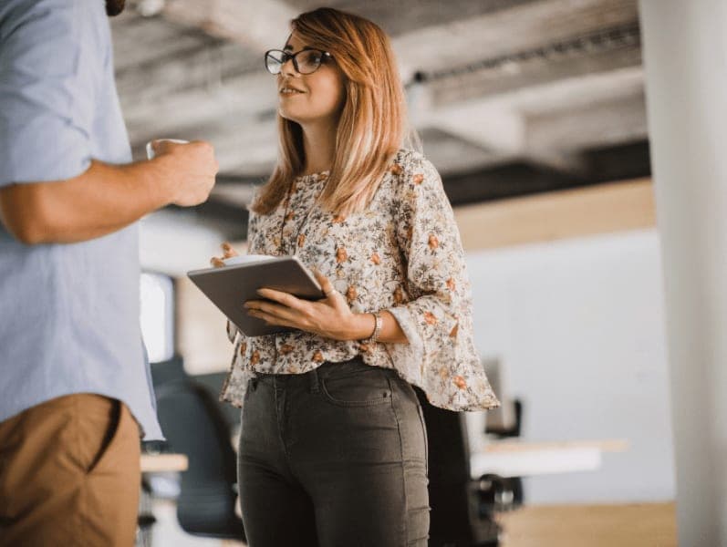 Female speaking with male colleague hold an ipad in front of her