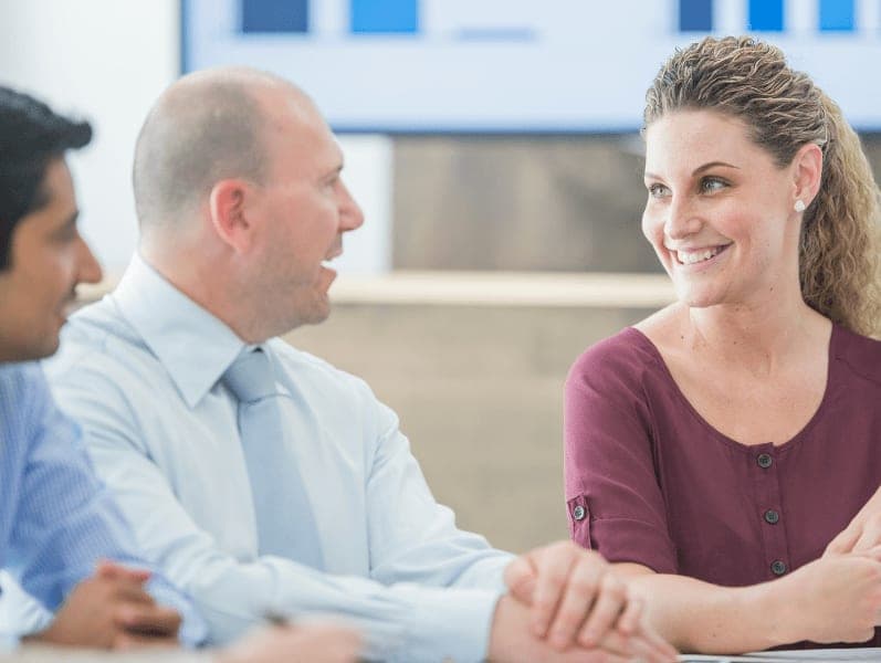 Female sitting beside male colleague smiling in his direction