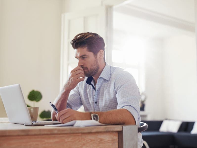 Man thinking while sitting at desk in front of his computer